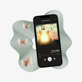 Phone with music app interface on a light gray background and three beige gradient butterflies